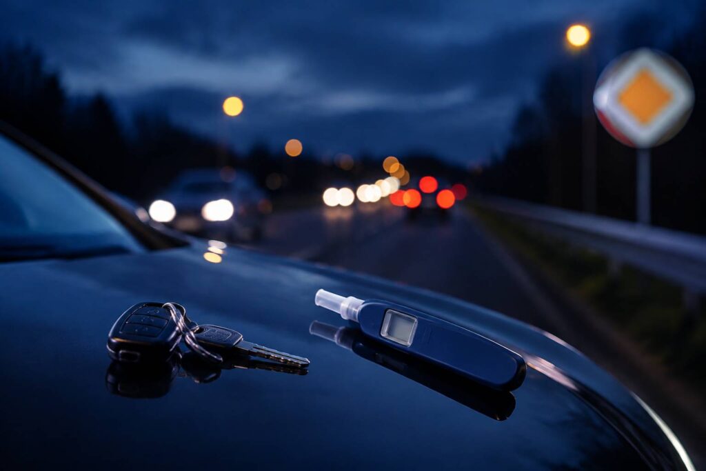 Éthylotest jetable posé sur un capot de voiture avec trousseau de clés au crépuscule